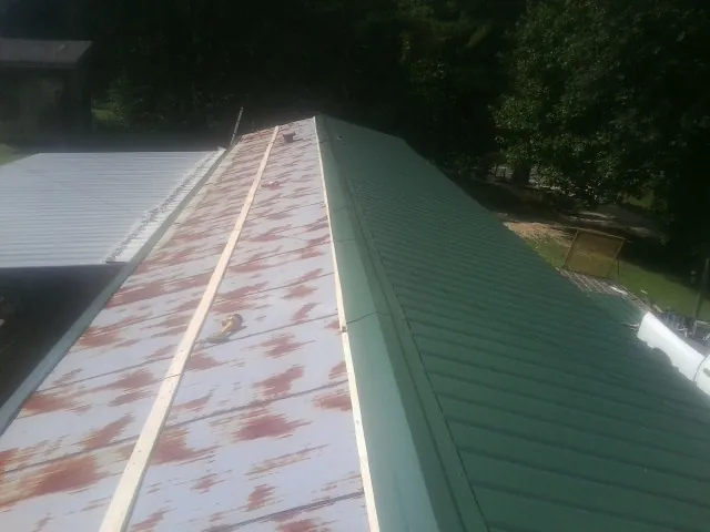 Old rusted panels beside newly installed green metal roofing — Wind Damage Roof Repair by Roofing Brothers in Hacienda Heights
