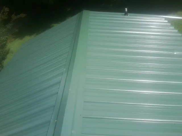 New green metal panels meeting at the ridge of a roof — Flat Roof Repair work by our crew in Hacienda Heights