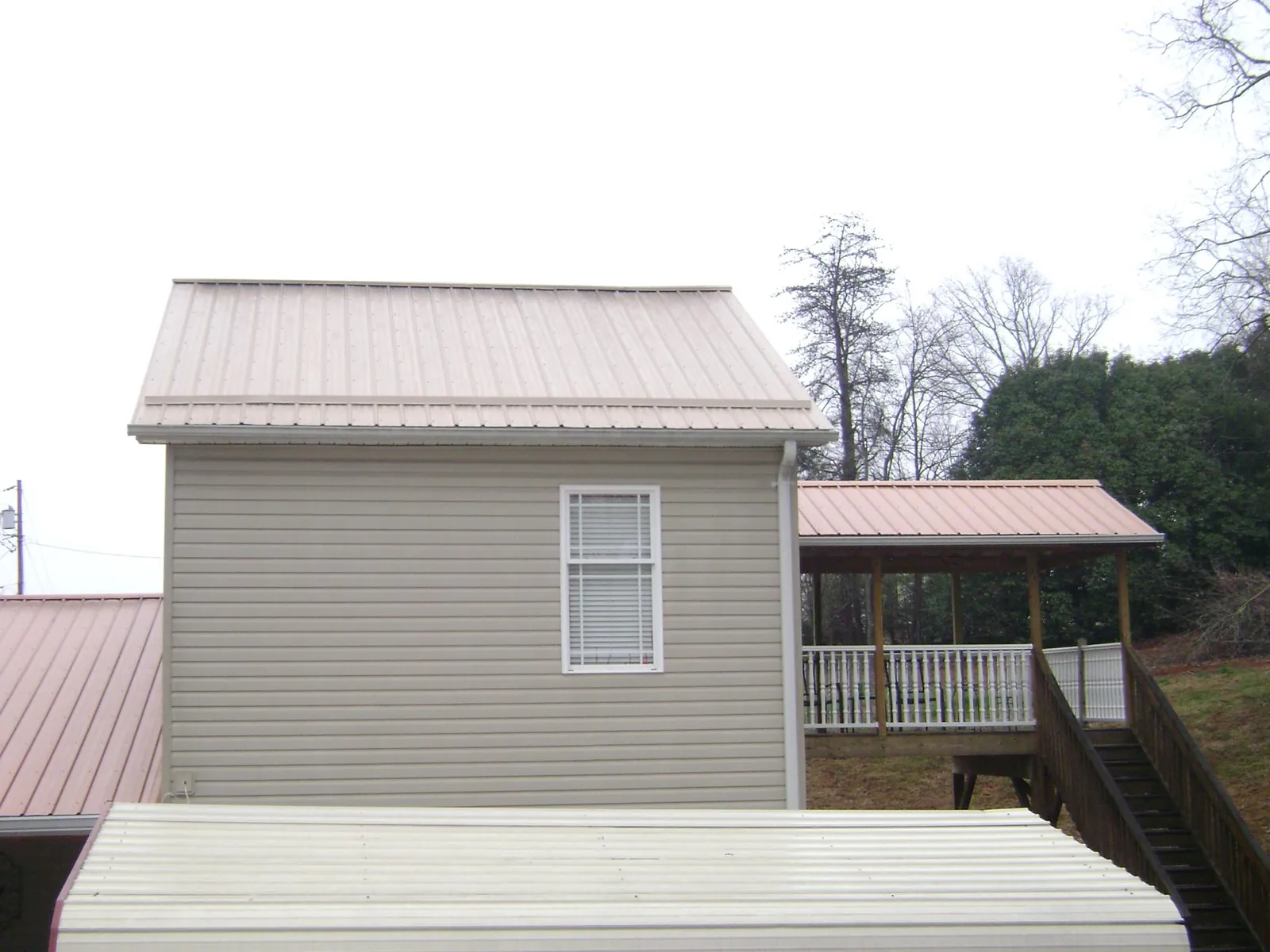 Tan metal roofs on a two story addition and attached porch, from a Roof Replacement job in Hacienda Heights