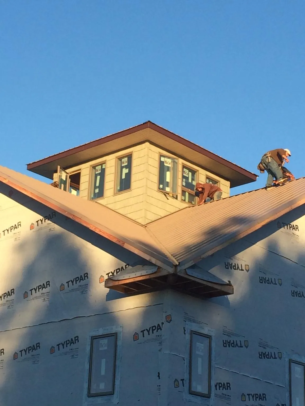 Roofers working around a rooftop cupola on a new metal roof at sunset — Roof Waterproofing in Hacienda Heights by Roofing Brothers